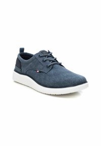 Zapatillas de deporte azul oscuro hechas de tela texturizada, con suela de goma blanca, punta redonda, diseño de cordones y un pequeño detalle de logo en el costado.