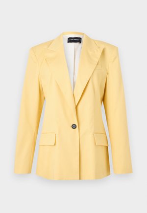 Κίτρινο σακάκι με ένα κουμπί, με γιακά με σχισμή και τσέπες με καπάκια, μακριά μανίκια και ελαφριά εσωτερική επένδυση.