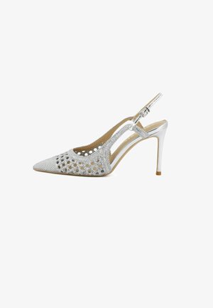 Scarpa slingback argento con tacco alto, punta appuntita, ritagli e decorazioni con strass, cinturino regolabile alla caviglia con fibbia.