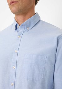 Helles blaues, knopfbares Hemd mit Kragen, ausgestattet mit einer aufgesetzten Tasche auf der linken Brust und glat...em, strukturiertem Stoff; klassisches Design.