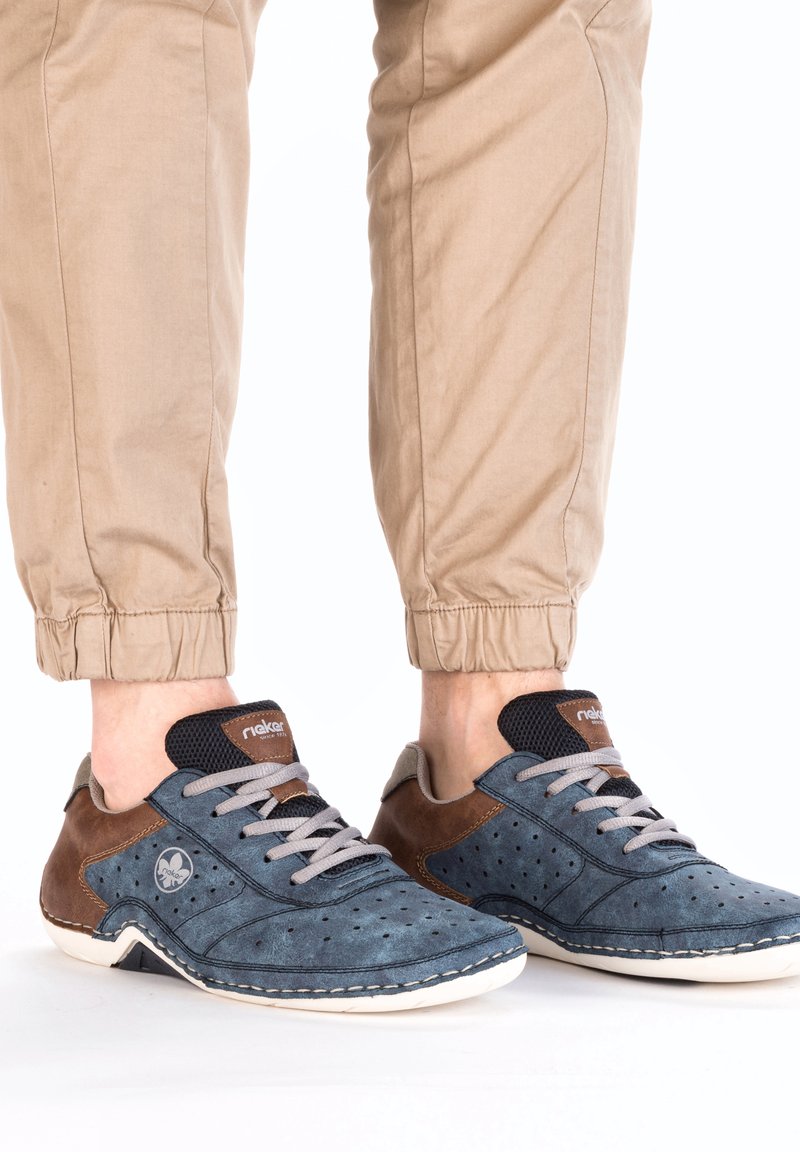 Blue and brown low-top sneakers made of suede, with perforated design, lace-up closure, and white rubber soles.