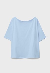 Chemise ample à manches courtes bleu clair avec un large décolleté, présentée à plat sur un fond neutre.