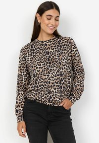 Dugog rukav majica s leopard uzorkom u boji smeđe i crne. Mekani materijal s ležernim krojem, okruglim izrezom i elastičnim manžetama. Uparena s tamnim trapericama.
