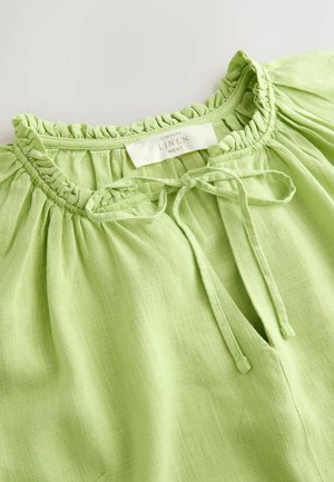 Hele roheline linane topp, millel on volditud kaelus rüüsäärega ja paeltihendiga, mis esitleb tekstuuriga hingavat kangast.