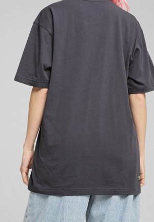 Ciemnoszary t-shirt o luźnym kroju, z krótkim rękawem, wykonany z bawełny, ze prostym dołem i akcentem z metką po boku, blisko brzegu.