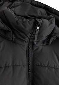 Schwarze isolierte Jacke mit hohem Kragen, durchgehendem Reißverschluss und gestepptem Design. Das Material wirkt glatt und hat ein weiches Innenfutter.