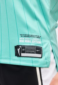 Τυρκουάζ αθλητική φανέλα New York Liberty Nike Rebel Edition με ταμπελάκι μεγέθους 40 και μότο για την αυτοθυσία και την αφοσίωση των γυναικών.