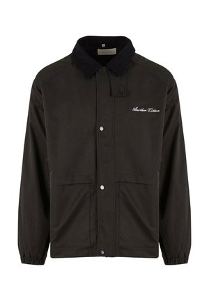 Black waterproof jacket featuring a corduroy collar, snap buttons, elasticized cuffs, and a front embroidered logo. Two lower pockets.
