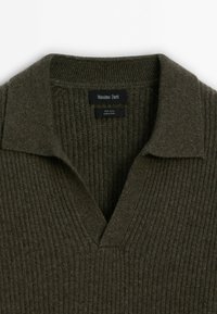 Pull en laine côtelé vert olive foncé avec col et encolure en V, avec étiquette de la marque Massimo Dutti et étiquette « Made in China ».