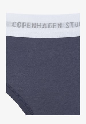 Slip di cotone blu navy con cintura elastica bianca sulla quale è stampato in grigio il testo "COPENHAGEN STUDIOS". Texture liscia, design aderente.