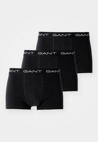 Drei schwarze Herren-Boxershorts mit schwarzen elastischen Taillenbändern mit weißem "GANT"-Schriftzug, diagonal auf weißem Hintergrund angeordnet.