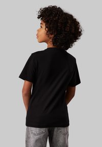 Calvin Klein Jeans MAXI HERO FLOCK LOGO - Apdrukāts T-krekls - black