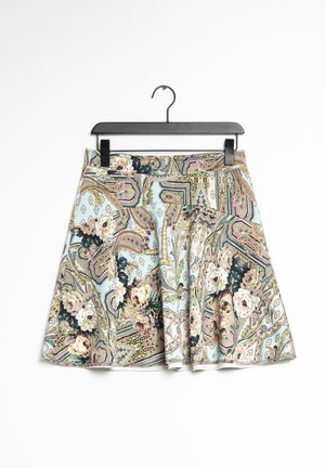 Udsvinget nederdel med pastel paisley- og blomsterprint i beige, grønne og blå nuancer, hængende på en sort klemmebøjle mod en hvid baggrund.