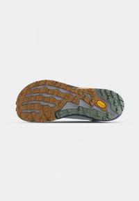 Semelle de chaussure de trail avec un motif texturé et robuste. Les variations de couleur comprennent le gris clair, le gris foncé et un brun terreux avec des accents verts.
