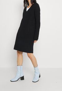 Svart stickad klänning med V-ringning och lång ärm. Matchad med ljusblå höga stövlar med dragkedja och tjock klack.