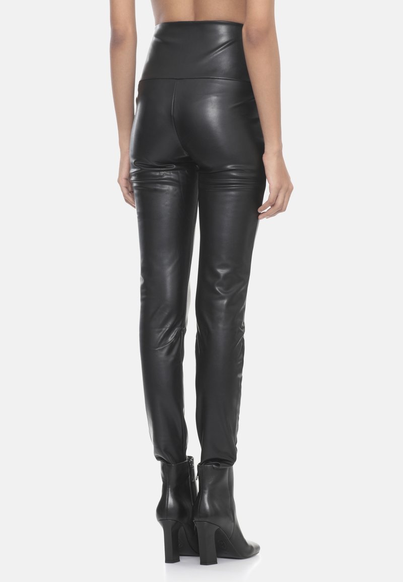 Pantaloni in pelle nera a vita alta con una texture liscia e una vestibilità su misura. Presentano un design elegante, senza hardware visibile, abbinati a stivali alla caviglia.