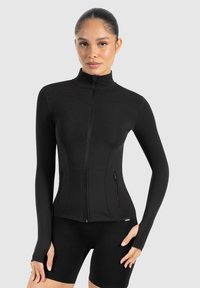 Svart långärmad zip-up jacka med hög krage, slim fit, platta sömmar och dragkedjefickor på sidan. Tillverkad av ett smidigt, elastiskt material.