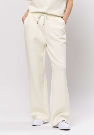 Široke hlače krem barve iz mehke tkanine, z elastičnim pasom z zavezovalnim trakom in stranskimi žepi.