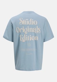 Camiseta de algodón azul cielo de mangas cortas, con una gran tipografía blanca en la parte de atrás que dice "Edición Original del Estudio".