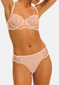 Lys pink lingeri sæt bestående af en balconette bh med blomsterlacedetaljer og matchende trusser med lacekant og gennemsigtige paneler.
