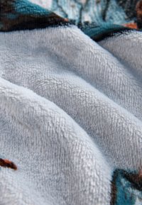 Close-up of soft, textured fabric with white and blue colors and slight folds creating shadows on the surface.