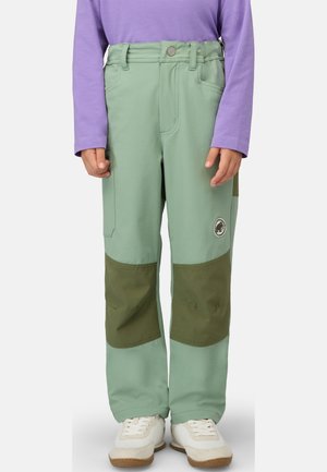 Child wearing light green pants with dark green knee patches, purple long-sleeve shirt, and white sneakers, standing against white background.