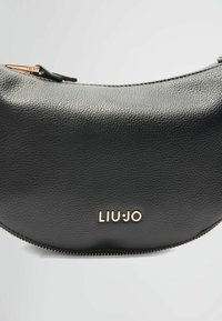Juodas odinis mėnulio formos rankinukas su tekstūruota paviršiumi, auksiniu įspaustu logotipu "LIUJO" ir auksine užtrauktuko apdaila.