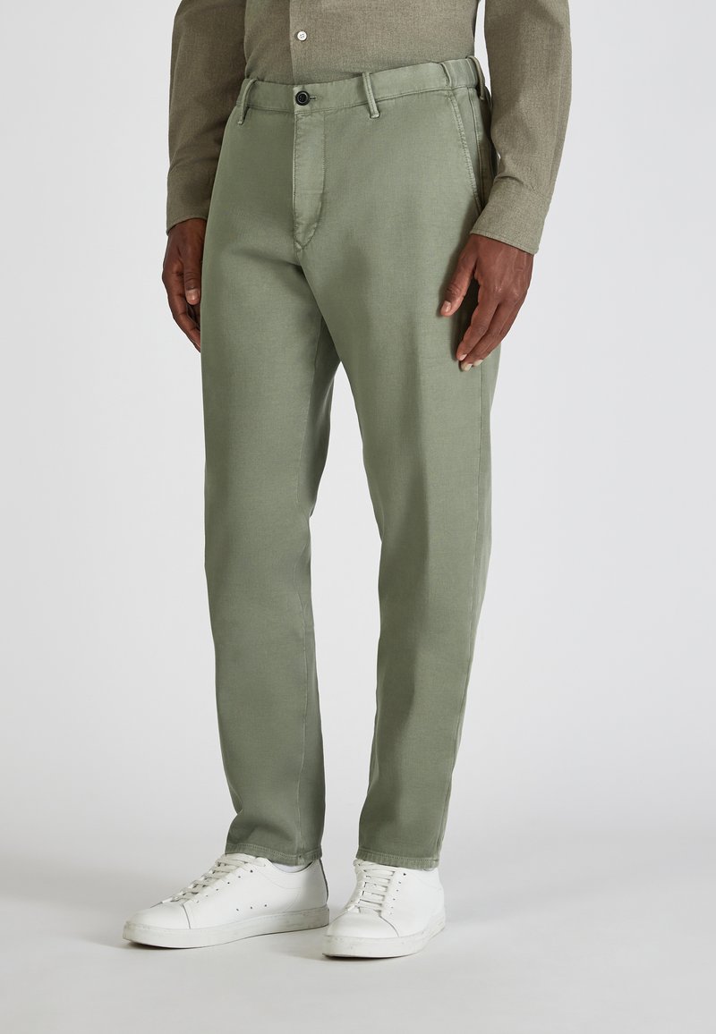 Groene katoenen broek met een slim fit, voorzien van een knoopsluiting en voorzakken, gecombineerd met witte sneakers.