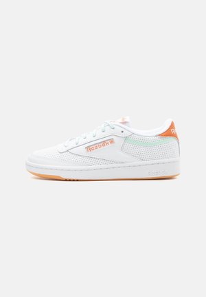 White Reebok low-top sneaker with perforated design, light blue laces, orange logo details, and a gum rubber sole on a plain background.