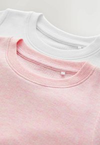Två crewneck sweatshirts: en rosa med en subtil textur och den andra i helt vitt, båda med ribbade kragar.