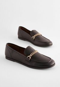 Black leather loafers with a textured finish, featuring a gold-toned chain accent across the front and a low profile sole.