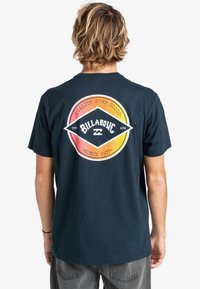Námorně modré bavlněné tričko s kulatou grafikou s přechodem z oranžové do žluté. Design obsahuje text "Quality Surf Goods" a "Billabong."