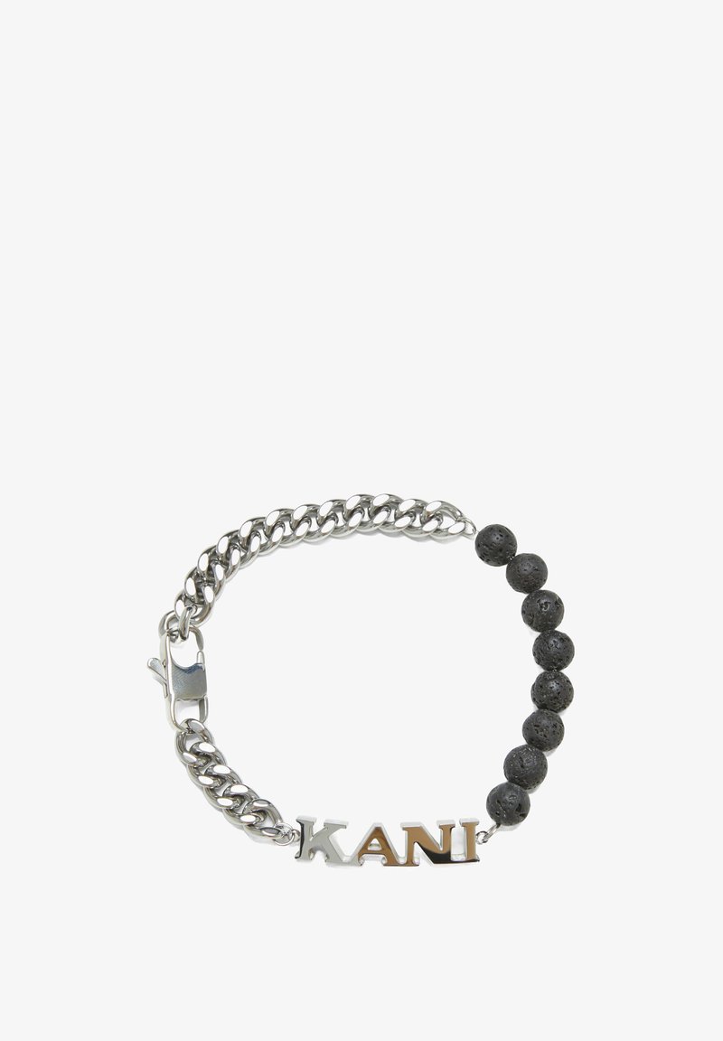 Sidabrinė grandinėlė su juodais lava akmens karoliukais, su pavadinimu "KANI" poliruoto sidabro apdaila. Uždarymo mechanizmas - omarų užsegimas.