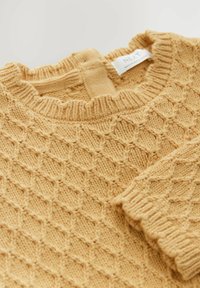 Pull en laine jaune tricoté mettant en avant un motif en losange, avec un col et des poignets côtelés. Le matériau semble doux avec une finition texturée. Étiquette de marque visible.