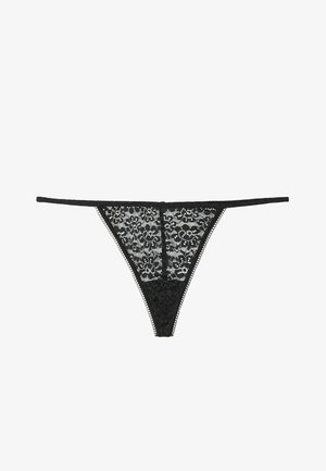 Tanga negro de encaje con patrón floral, que presenta tiras laterales delgadas, bordes con picos y un frente transparente, destacando un detalle intrincado.