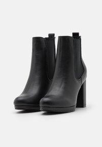 Černé kožené kotníkové boty s hladkým povrchem, zaoblenou špičkou a středním blokovým podpatkem. Disponují elastickými bočními panely pro snadné obouvání.