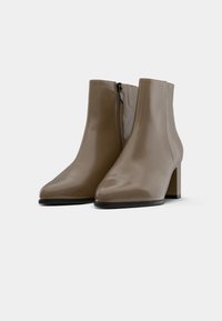 Braune, glatte Lederstiefeletten mit spitzer Zehenform und Blockabsatz; verfügen über einen seitlichen Reißverschluss zum Schließen. Niedrigprofilierte schwarze Laufsohle.