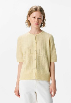 Kortärmige, lichtgele cardigan met een gestructureerd gebreid ontwerp en kleine parelknoopjes aan de voorkant. Zacht, lichtgewicht materiaal.