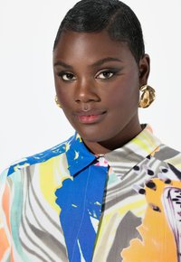 Blusa con colletto dallo splendido motivo astratto in blu, giallo e arancione, dotata di una chiusura frontale con bottoni e una texture seta.