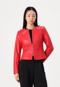 Rote Kunstlederjacke mit taillierter Passform, rundem Halsausschnitt und Reißverschluss. Mit langen Ärmeln und Volantsaum.