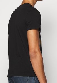 Zwarte katoen t-shirt met een ronde hals, korte mouwen en een eenvoudige achterkant, gecombineerd met blauwe spijkerbroek.