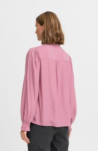 Langärmlige rosa Bluse mit gerafften Schultern, geknöpften Manschetten und geradem Schnitt. Glatte Textur und klassischer Kragen.