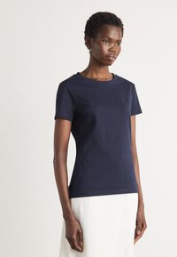 T-shirt in cotone blu navy con maniche corte, collo rotondo, vestibilità slim e sottile dettaglio del logo sul petto. Texture liscia, design minimale.