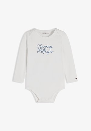 Bijeli baby bodi s dugim rukavima s natpisom "Tommy Hilfiger" plavim kurzivnim slovima sprijeda i malim logom zastave Tommy Hilfiger na manžeti lijevog rukava.