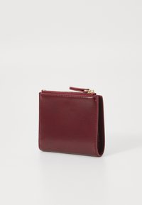 Portafoglio in pelle bordeaux con texture liscia, chiusura con zip e hardware color oro. Forma compatta e rettangolare con dettagli di design minimali.