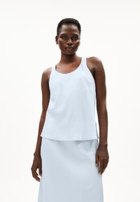 Light blue sleeveless top with a round neckline, made of smooth fabric. It features a flowing design and delicate stitching at the edges.