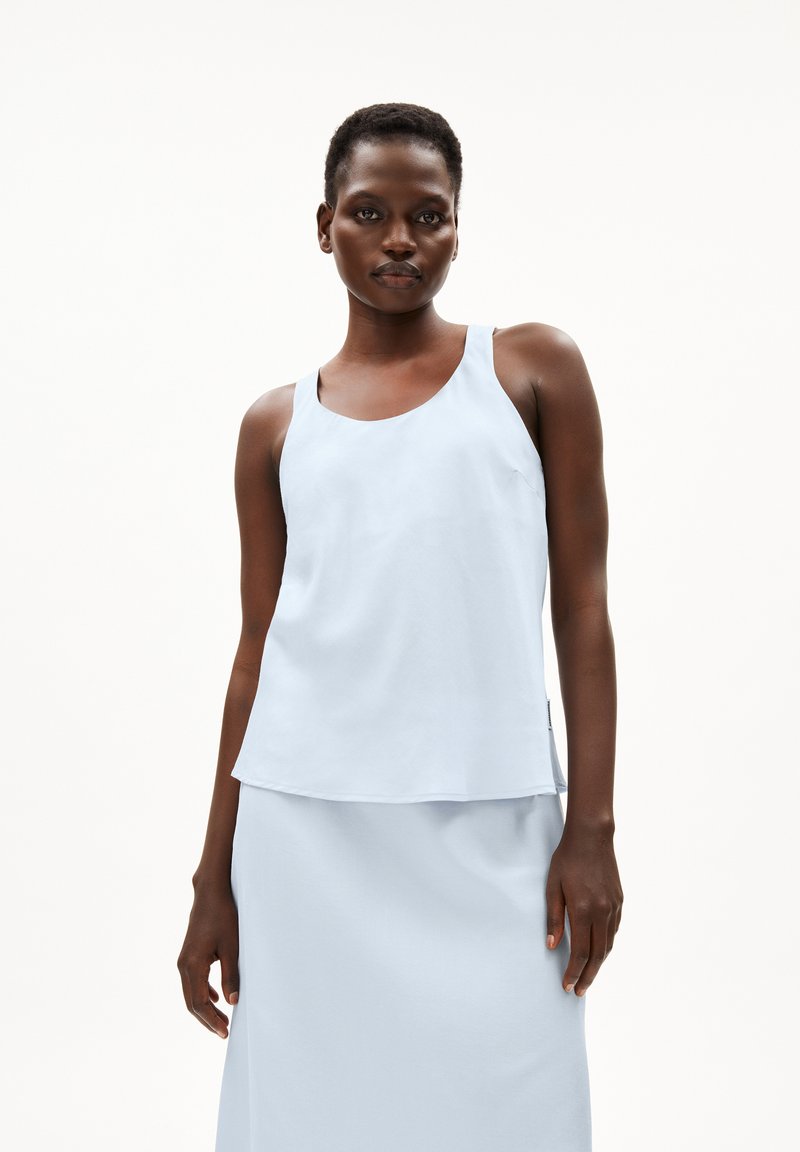 Light blue sleeveless top with a round neckline, made of smooth fabric. It features a flowing design and delicate stitching at the edges.
