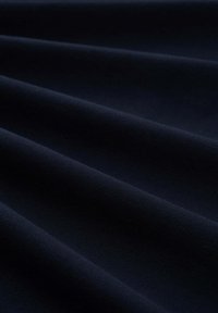 Ciemnoniebieska tkanina o fakturowanym, tkanym wzorze, prezentująca delikatne fałdy i subtelną poświatę, idealna do tapicerki lub odzieży.