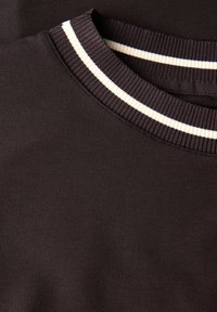 Black sweatshirt featuring a ribbed collar with white and cream stripes. Soft texture with a classic crew neckline design.