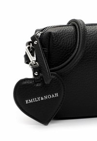 Schwarze handgefertigte Lederhandtasche mit metallischen Akzenten. Ausgestattet mit einem herzförmigen Anhänger, auf dem "EMILY&NOAH" in Silber eingeprägt ist. Mit Reißverschluss.